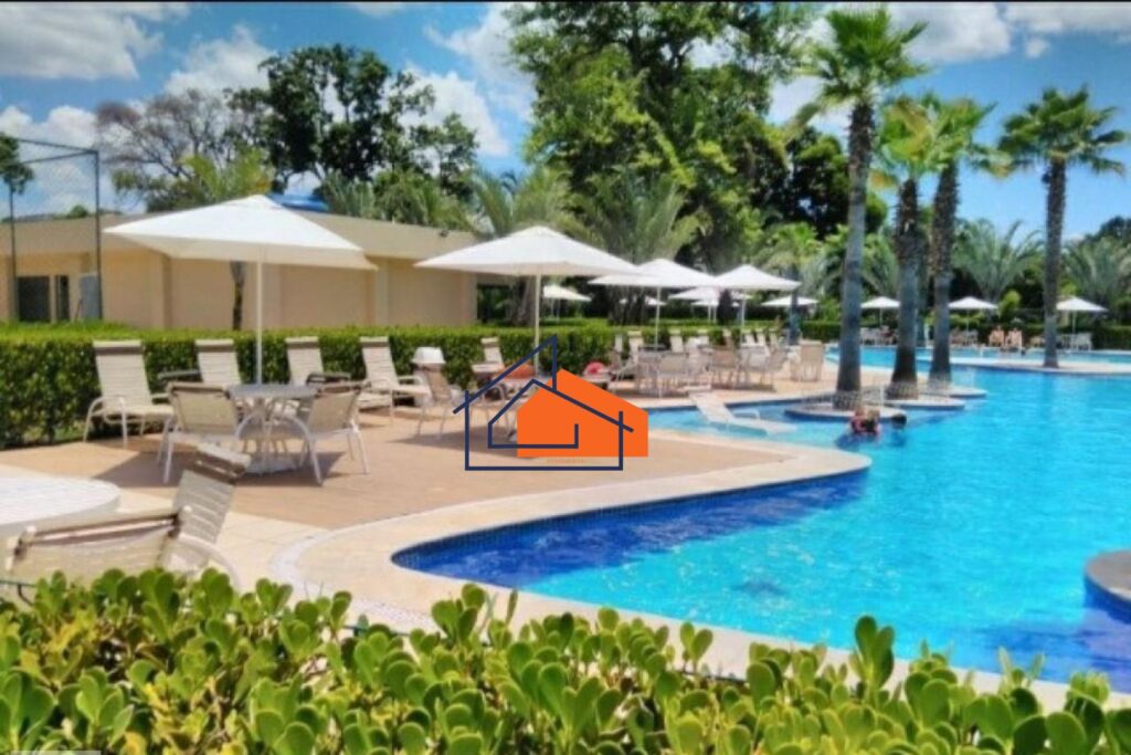 Piscina externa com espreguiçadeiras, mesas com guarda-sóis brancos e árvores ao redor.